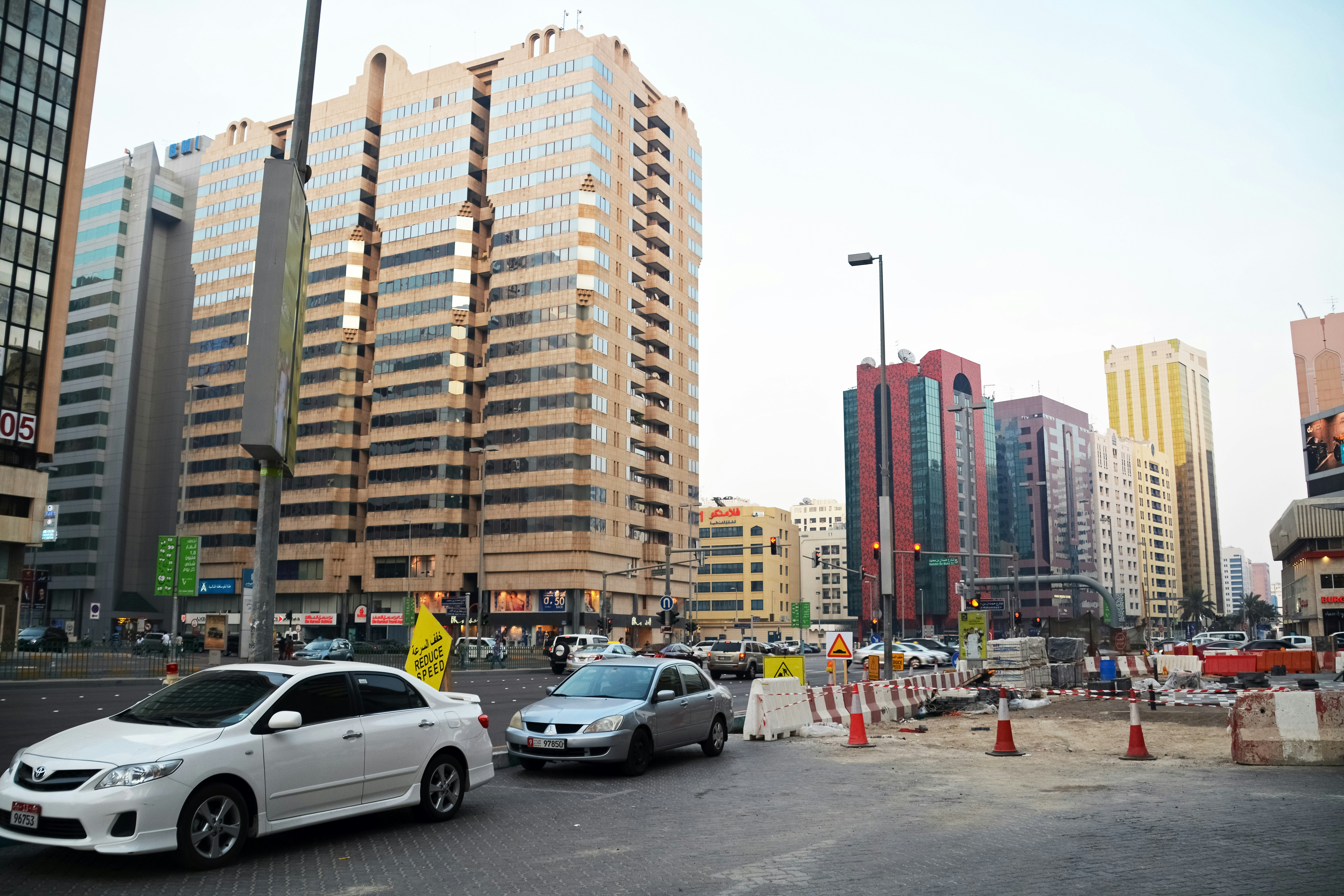 cars parked on parking lot near high rise buildings during daytime